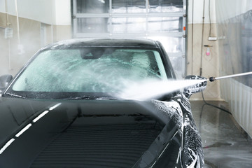 Cleaning automobile with high pressure water jet at car wash