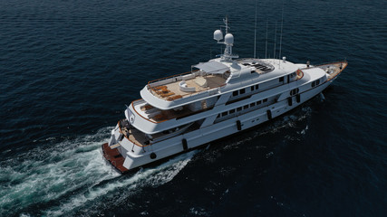 Fototapeta premium Aerial drone photo of luxury yacht cruising deep blue sea in Mediterranean Aegean island destination located in Greece