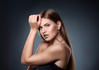 Fototapeta premium Portrait of beautiful lady with gold lipstick on grey background