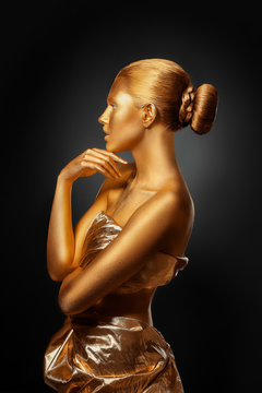 Portrait of beautiful lady with gold paint on skin against black background