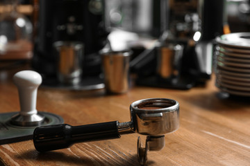 Portafilter with milled coffee on wooden bar counter. Space for text