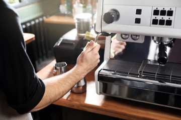 Barista cleaning coffee machine steam wand with rag on bar counter, closeup