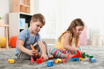 Little children playing with colorful blocks indoors