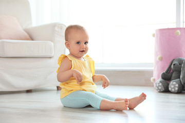 Fototapeta premium Cute baby girl sitting on floor in room