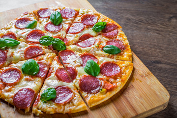 Pepperoni Pizza with Mozzarella cheese, salami, Tomato sauce, pepper, Spices and Fresh basil. Italian pizza on wooden table background