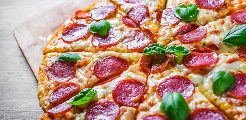Pepperoni Pizza with Mozzarella cheese, salami, Tomato sauce, pepper, Spices and Fresh basil. Italian pizza on wooden table background