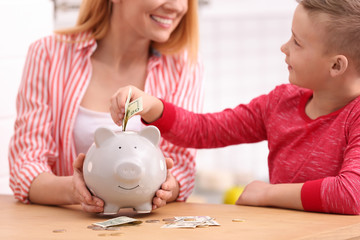 Obraz na płótnie Canvas Family with piggy bank and money at table