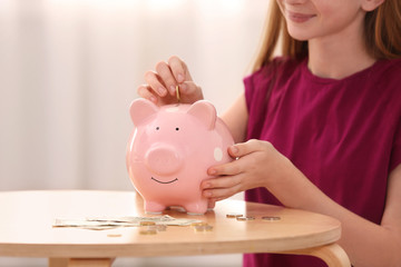 Obraz na płótnie Canvas Teen girl with piggy bank and money at home, closeup