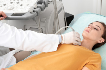 Doctor conducting ultrasound examination of patient's neck in clinic