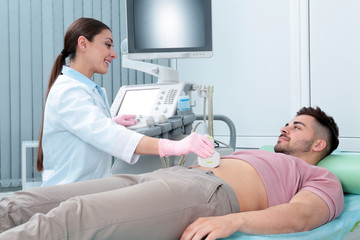 Doctor conducting ultrasound examination of patient's abdomen in clinic