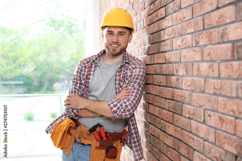 Wall mural young working man in hardhat near brick wall