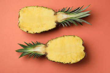 Halves of fresh pineapple on orange background, top view