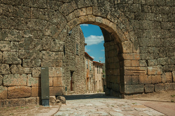 Old house seen through arch gate from a stone wall