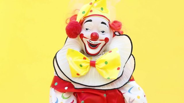 Clown toy with yellow background head explodes in slow motion