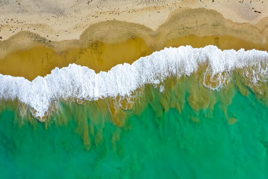 Drone aerial of waves mixing with sand off of the Southern California coast