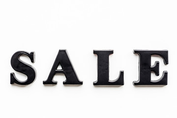 The inscription SALE. SALE in black bulk letters on a white background. Photo of the lettering, close-up