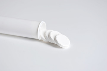 White tablets are poured out of a white plastic bottle. Tablets for dissolving in water. Healthcare concept. Space for text placement. Close-up. White background.