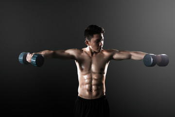Fototapeta na wymiar Asian man exercising his biceps with dumbbells