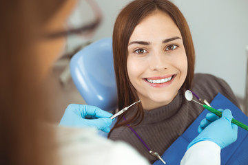 Smiling girl treats teeth while sitting in the dental chair at the doctor.