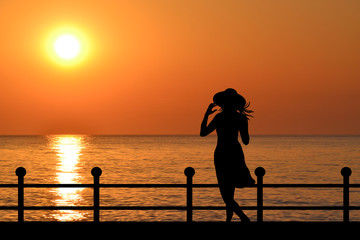 Silhouette of a woman on the waterfront at sunrise