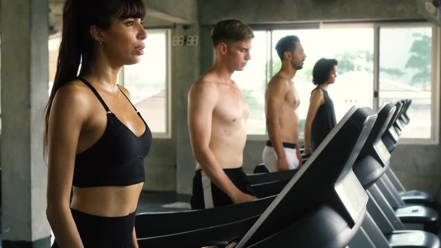 Row of Caucasian people exercising on treadmills at modern gym. Fitness men and women working out together