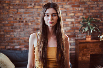 Naklejka premium Portrait of beautiful young woman with long broun hair over brick wall background.