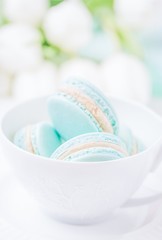 Mint or tiffany color macaron or macaroon dessert with vanilla cream in white cup. Copy space