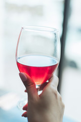 A girl with a gentle nude manicure holding a glass of cherry frothy beer.