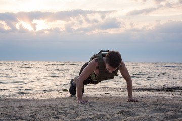 Young bearded athlete training outdoor with weighted vest,  exercise with military plate carrier