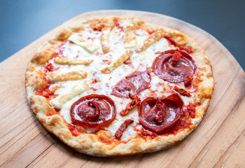 Delicious, fresh and tasty flat bread italian pepperoni or margherita pizza. View of Salami, cheese and basil pizza in restaurant at napoli. Pizza on wooden pizza shovel board.