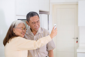 Elderly couple taking a selfie together at home