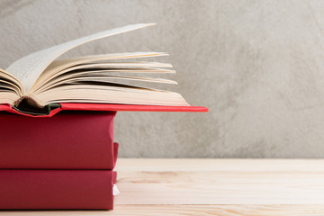 Education and reading concept - group of colorful books on the wooden table, concrete wall blackboard