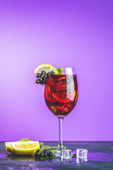 Cold red cocktail in tall glass on violet background