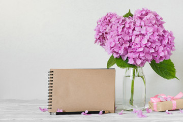 blank greeting card with pink hydrangea flowers and gift box on white background. modern still life