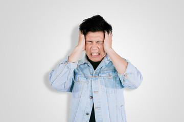 Frustrated young man touching his head on studio