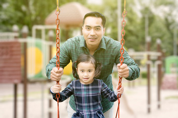 Happy man playing on a swing with his daughter