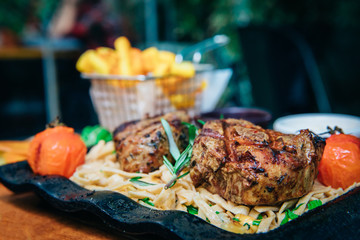 Grilled or roasted beef steak meat and pasta food meal with french fries potatoes in cafe or restaurant. Dinner or lunch table concept image