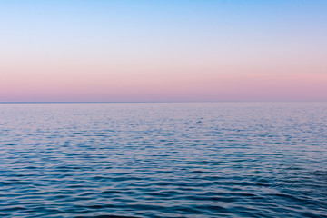 Seascape background, a hazy colorful sunset after a hot summer day over calm sea water, Vis island, Croatia