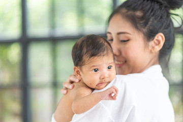 A young mother carries a baby