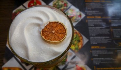 Delicious cocktail with cream and dried lime in the bar on the background of the menu. Background for bars, restaurants, cafes.
