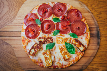 Delicious, fresh and tasty flat bread italian pepperoni or margherita pizza. View of Salami, cheese and basil pizza in restaurant at napoli. Pizza on wooden pizza shovel board.