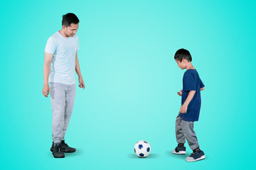 Little child passes a football to his father on studio