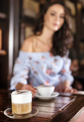 Blurred portrait of a brunette woman in a cafe
