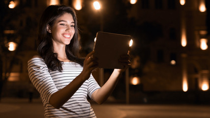 Blogger showing city at night, using tablet , copy space © Prostock-studio