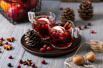 Mulled wine in glasses on a wooden background. Apples, cranberries, cinnamon, star anise.