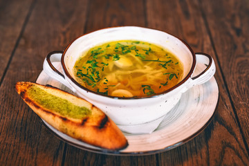 Chicken soup in a plate with toasted slices of bread on the side