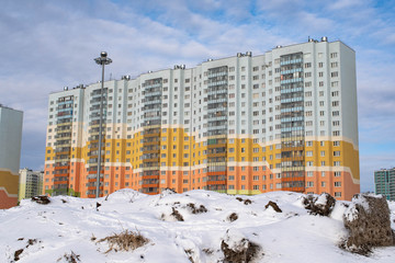 residential high-rise buildings on the background of dirty snowy hills