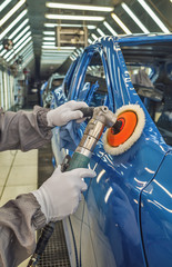 Employee in the shop painting the car body polishes painted body parts