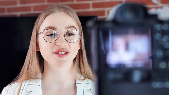 Close-up smiling face of beautiful young girl blogger talking recording using professional camera