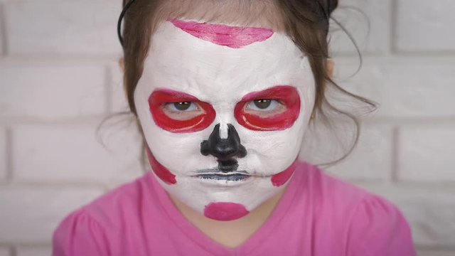 Angry child for Halloween. Little girl with painted face for halloween.